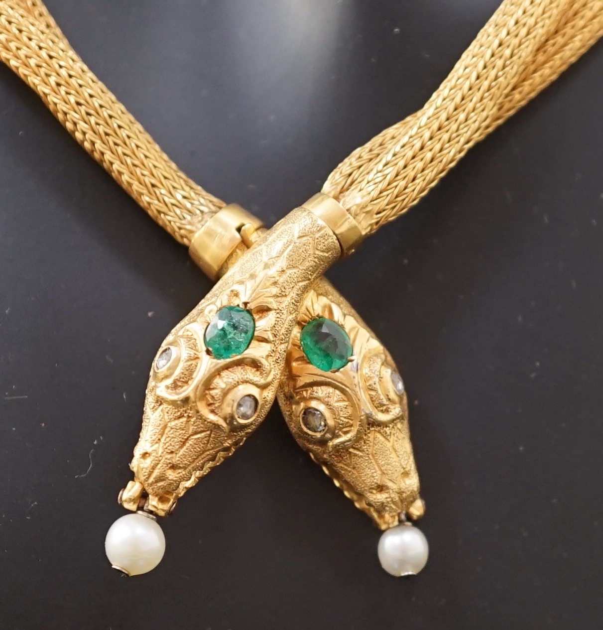 An early 20th century multi-strand gold, emerald, rose cut diamond and cultured pearl drop set twin headed serpent necklace